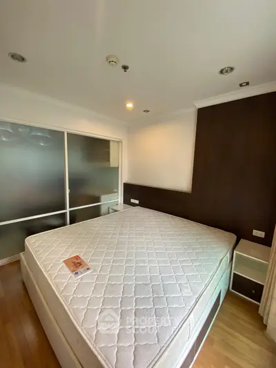 Spacious bedroom with large bed and wooden flooring, featuring modern sliding door closet.