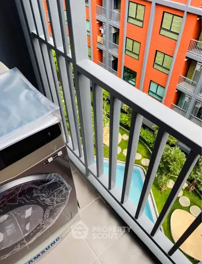 Modern balcony view with washing machine overlooking pool and garden in vibrant apartment complex.