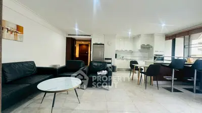 Modern open-layout living room and kitchen with sleek furniture and bright lighting.