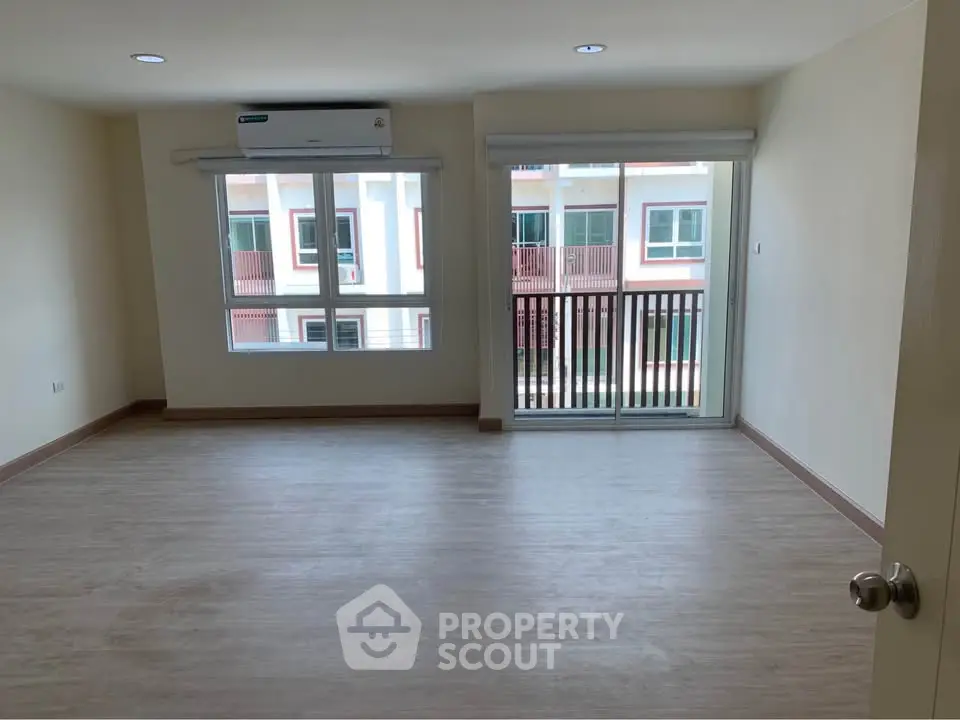 Spacious empty living room with large windows and balcony access in modern apartment.