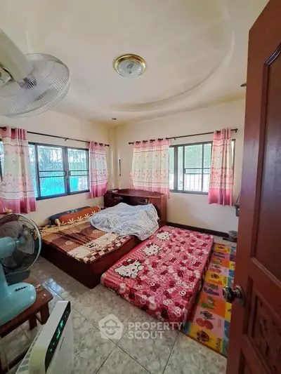 Cozy bedroom with colorful bedding and ample natural light from multiple windows.