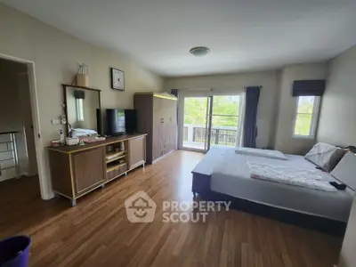 Spacious bedroom with balcony and wooden flooring in modern apartment