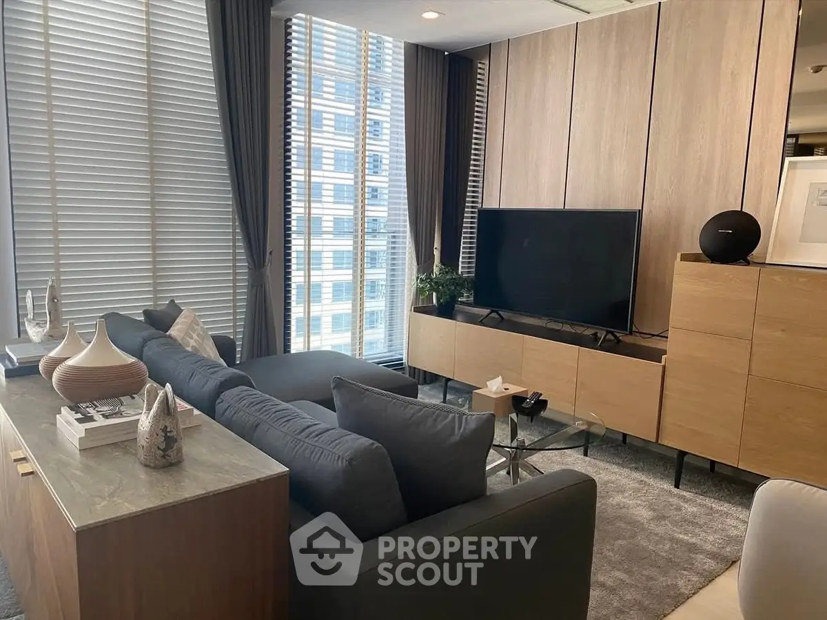 Modern living room with sleek furniture and large windows offering city views.
