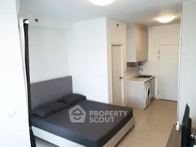Modern studio apartment with sleek design, featuring a cozy bed and in-unit washing machine.
