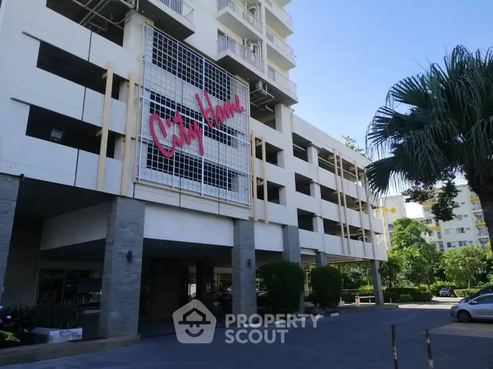 Modern apartment building exterior with lush greenery and ample parking space.