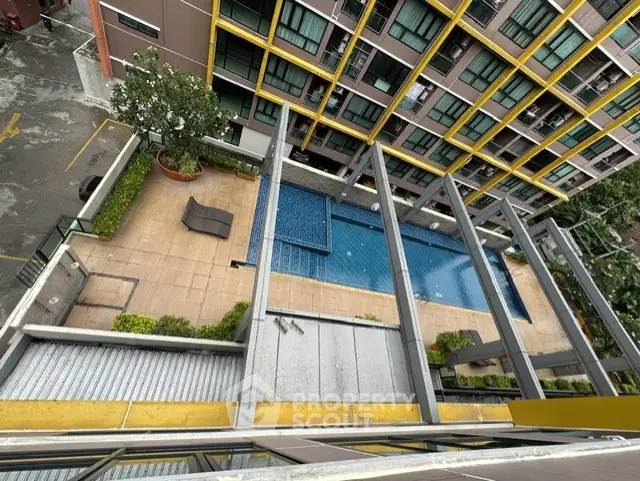 Modern apartment building with pool view from above, showcasing vibrant architecture and inviting outdoor amenities.