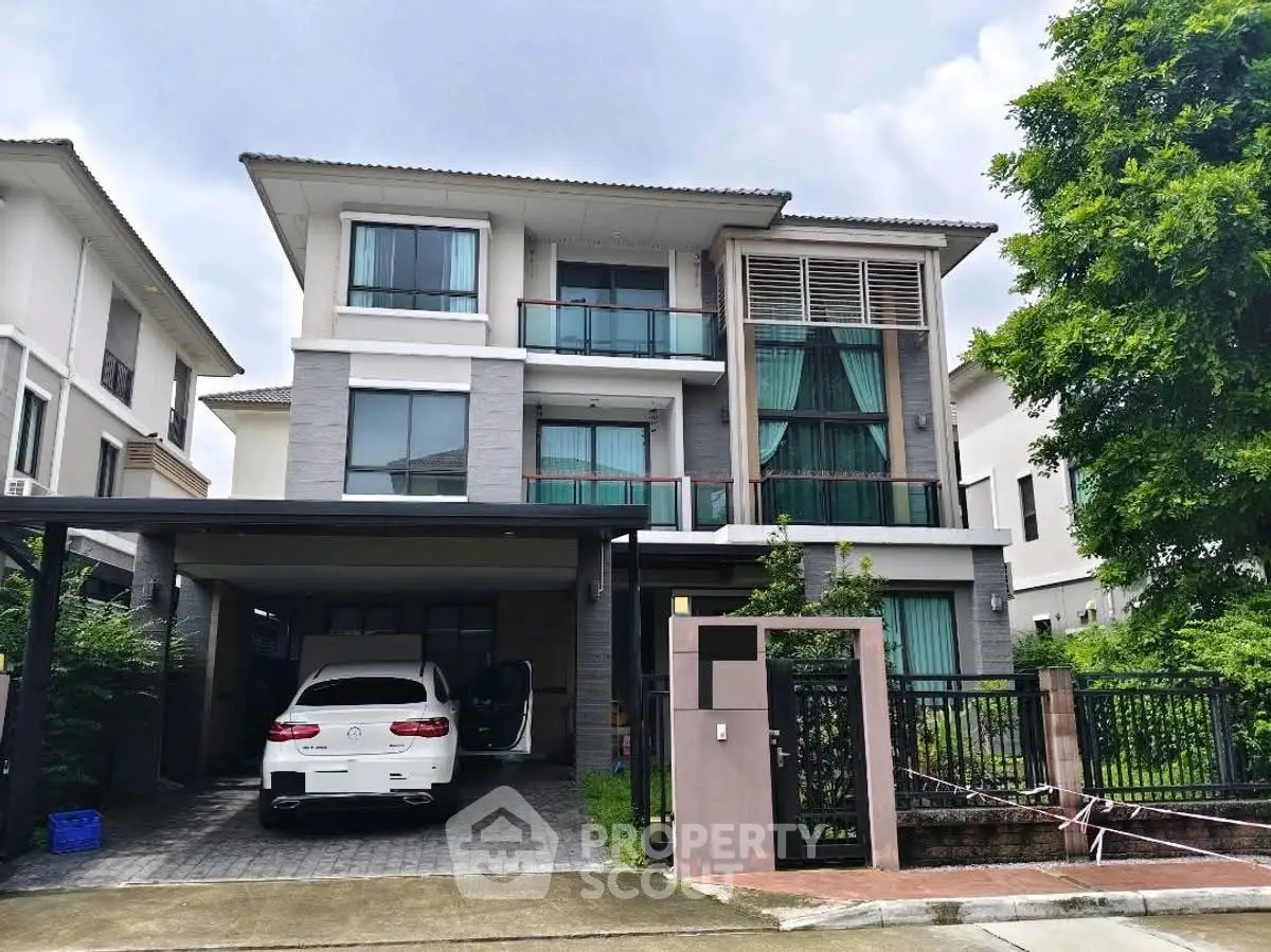 Modern three-story house with carport and lush greenery in a serene neighborhood.