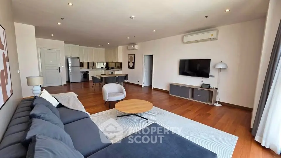 Spacious modern living room with open kitchen, hardwood floors, and stylish furnishings.