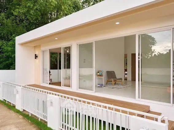Modern minimalist home with large sliding glass doors and spacious wooden deck.