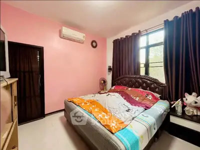 Cozy bedroom with colorful bedding and natural light, featuring air conditioning and modern furnishings.