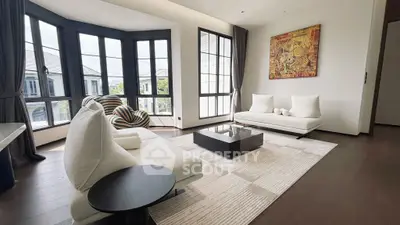 Elegant living room with modern furniture and large windows offering natural light.