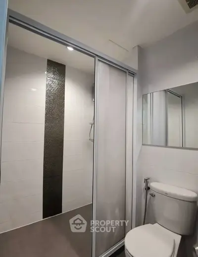 Modern bathroom with sleek shower and toilet in minimalist design.