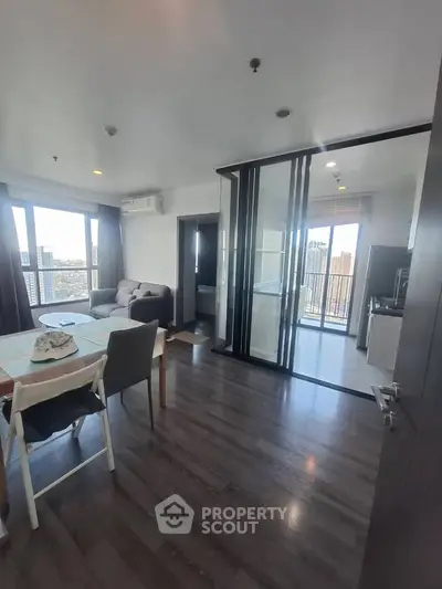 Modern apartment with open layout, large windows, and city view, featuring a cozy living area and sleek kitchen.
