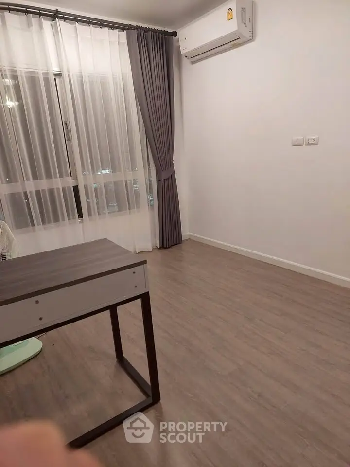 Spacious room with modern flooring and large window, perfect for a cozy living space.