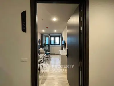 Modern apartment entrance leading to a stylish living room with sleek furnishings and natural light.