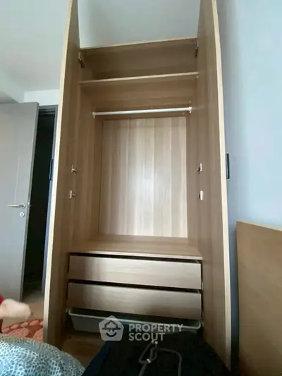 Spacious wooden wardrobe with open doors and drawers in a modern bedroom.