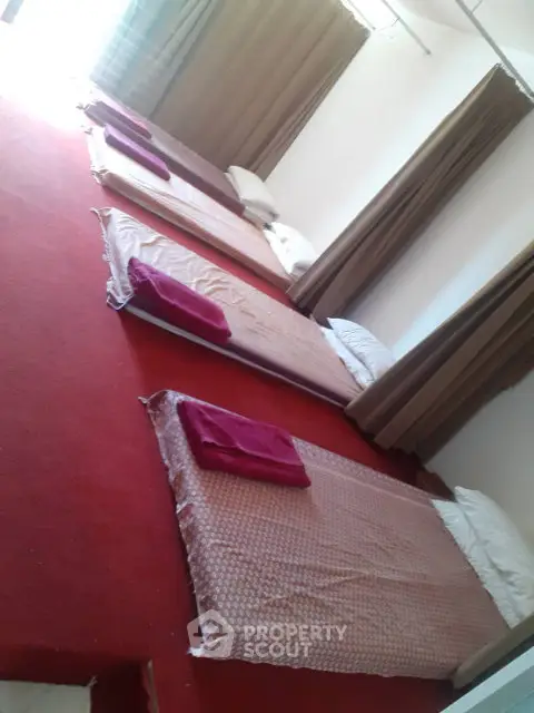 Spacious room with multiple floor mattresses and red carpet, ideal for shared accommodation.