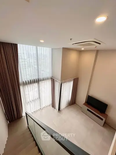 Spacious modern living room with high ceilings and large windows offering city views.