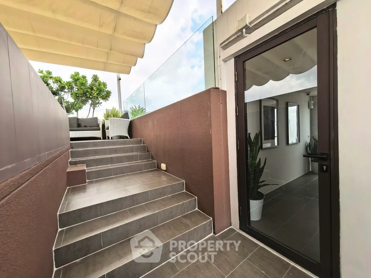 Stylish rooftop terrace with modern glass railing and cozy seating area.
