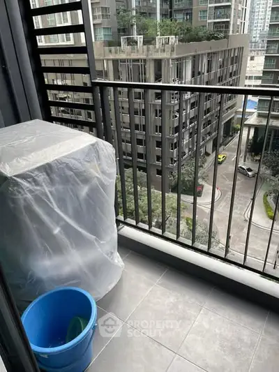 Modern balcony with city view, featuring a covered appliance and sleek railing design.