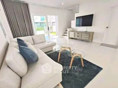 Modern living room with stylish furniture and large TV, bright and inviting space.