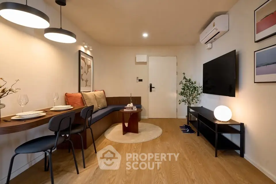 Modern living room with stylish decor, featuring a cozy dining area and sleek entertainment setup.