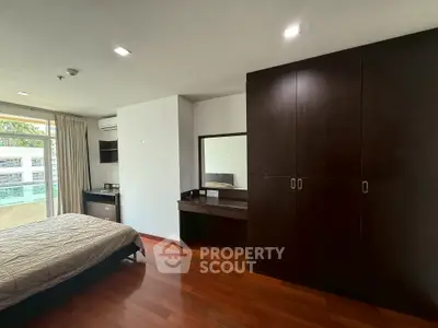 Spacious bedroom with elegant wooden flooring and ample natural light.