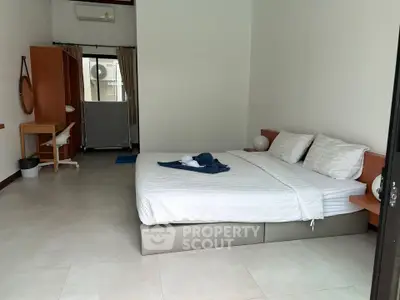 Spacious bedroom with modern furnishings and natural light, perfect for relaxation.