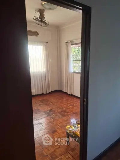 Spacious room with wooden flooring and natural light, ideal for cozy living.