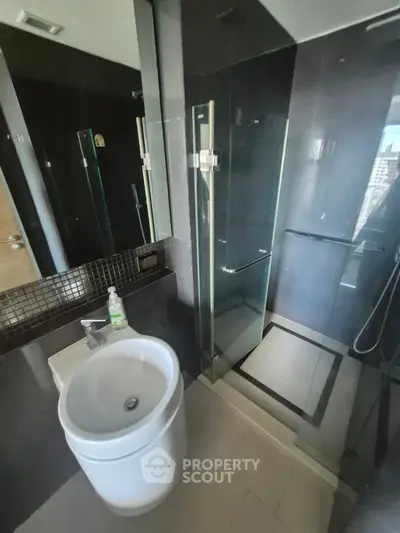 Modern bathroom with sleek black tiles and glass shower enclosure