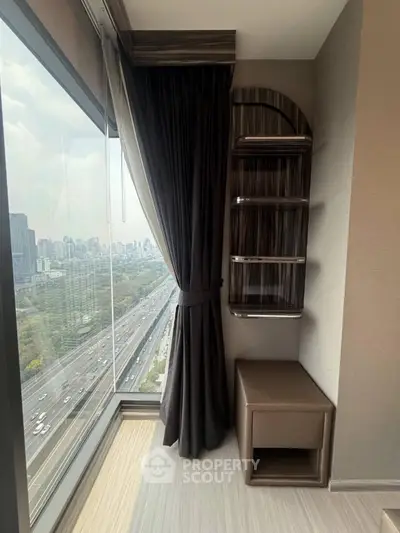Stunning high-rise view from modern apartment corner with elegant curtains and shelving.