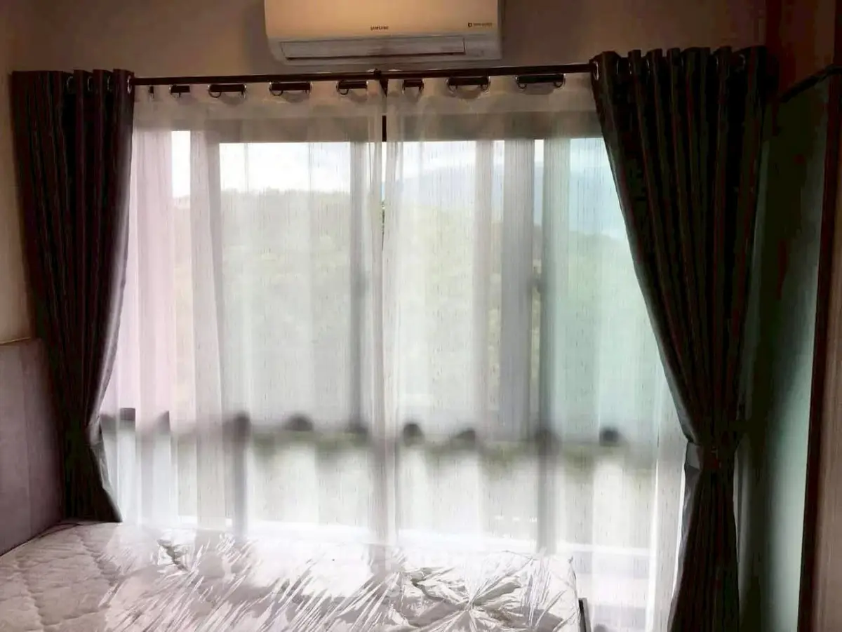 Cozy bedroom with large window and air conditioning, offering natural light and scenic views.