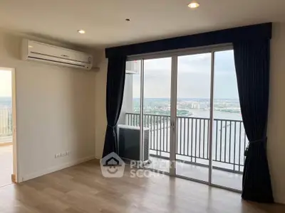Spacious living room with large windows offering stunning river view and balcony access.