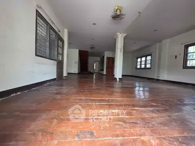 Spacious empty living room with wooden flooring and ample natural light.