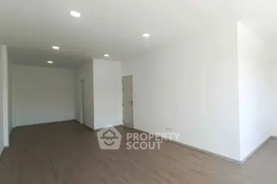 Spacious empty room with wooden flooring and white walls, ideal for customization.