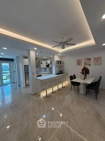 Modern open-layout kitchen and dining area with sleek design and elegant lighting.