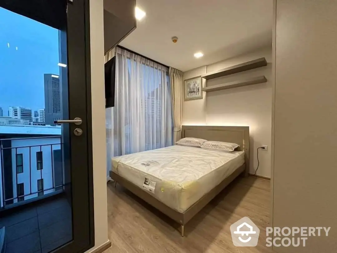 Modern bedroom with a large comfortable bed, sleek design, and access to a private balcony boasting a city view, perfect for urban living.