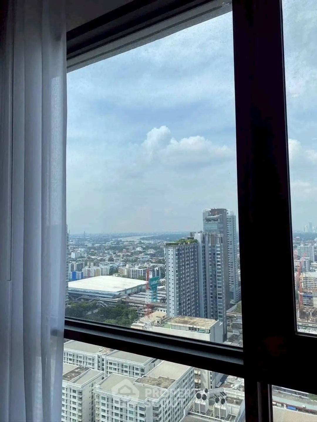 Stunning cityscape view from high-rise apartment window with clear skies.