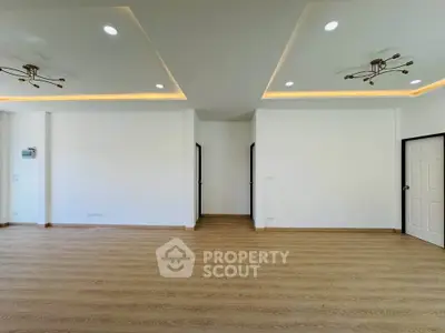 Spacious modern living room with elegant lighting and wooden flooring, perfect for family gatherings.