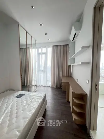 Modern bedroom with large window and city view, featuring sleek furniture and ample natural light.