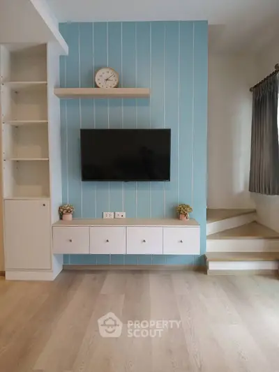 Modern living room with stylish TV wall, built-in shelves, and elegant staircase.