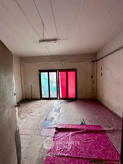 Spacious room with large windows and potential for renovation