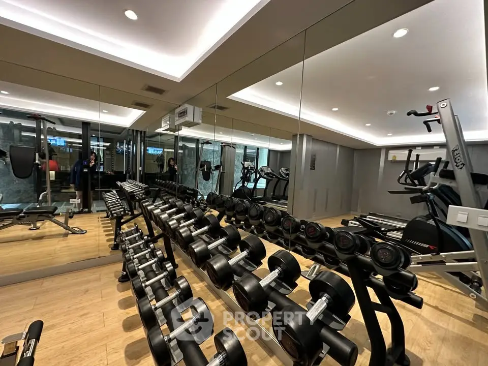 Modern gym with mirrored walls and state-of-the-art fitness equipment in luxury residential building.