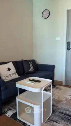 Cozy living room with modern furniture and wall clock, perfect for relaxation.