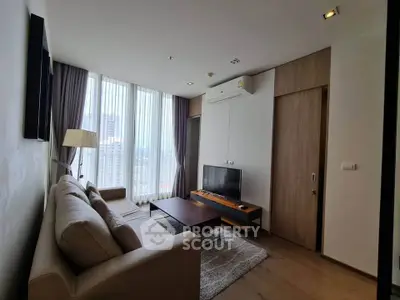 Modern living room with large windows and city view, featuring a cozy sofa and sleek TV setup.