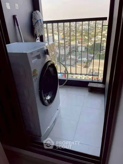 Compact balcony with washing machine and city view, ideal for urban living convenience.
