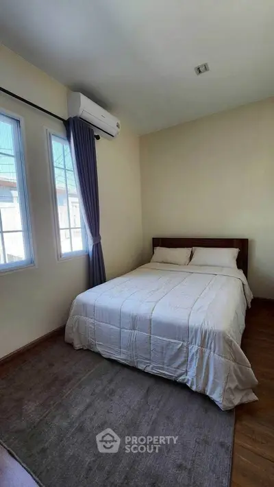 Cozy bedroom with natural light and air conditioning, perfect for relaxation.