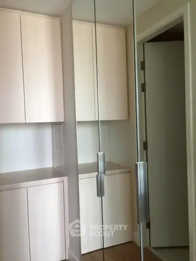 Modern storage area with sleek cabinetry and mirrored doors in a contemporary home.