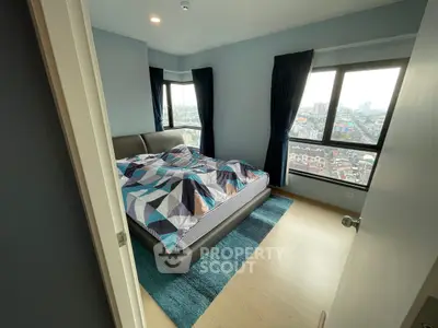 Modern bedroom with city view, featuring stylish decor and large windows for natural light.