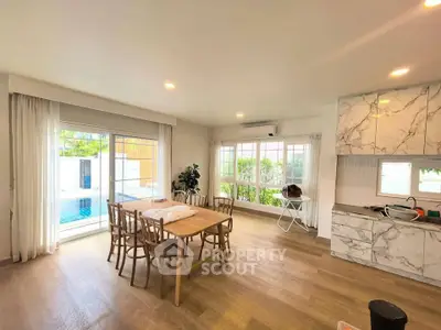 Spacious open-plan living room with dining area and pool view, featuring modern decor and natural light.
